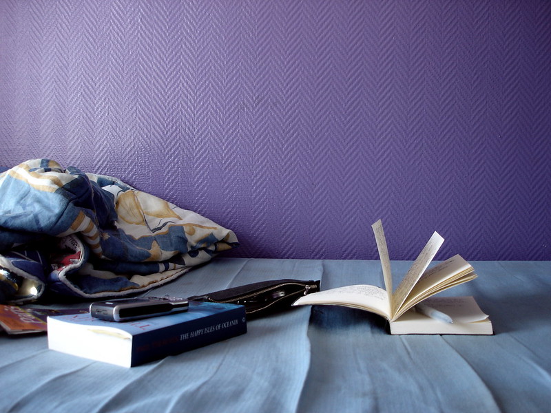 Book, diary, phone, and purse on a hostel bed