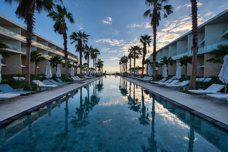 Lounge chairs around a resort pool near sunset